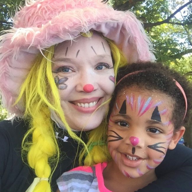 Corky Magic displaying her face painting with little girl with face painted like a cat